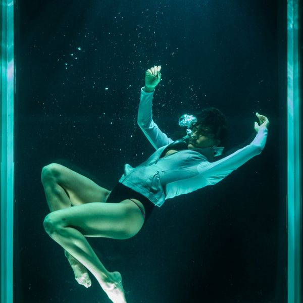 Person in a fluid yoga movement in a dark room.